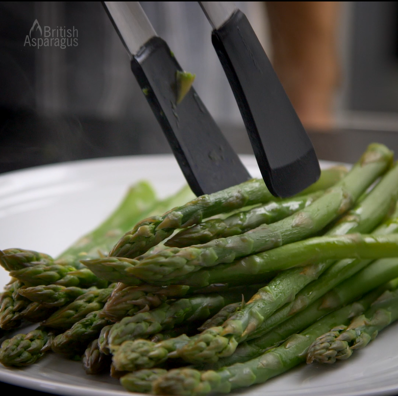 Steamed asparagus being put onto a plate
